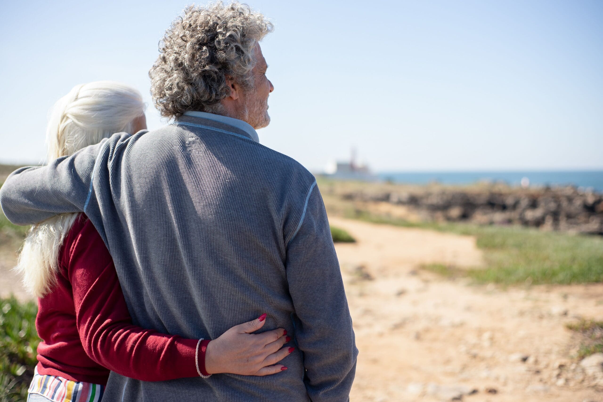 A middle-aged couple walking together on a beach, reflecting on life and connection.